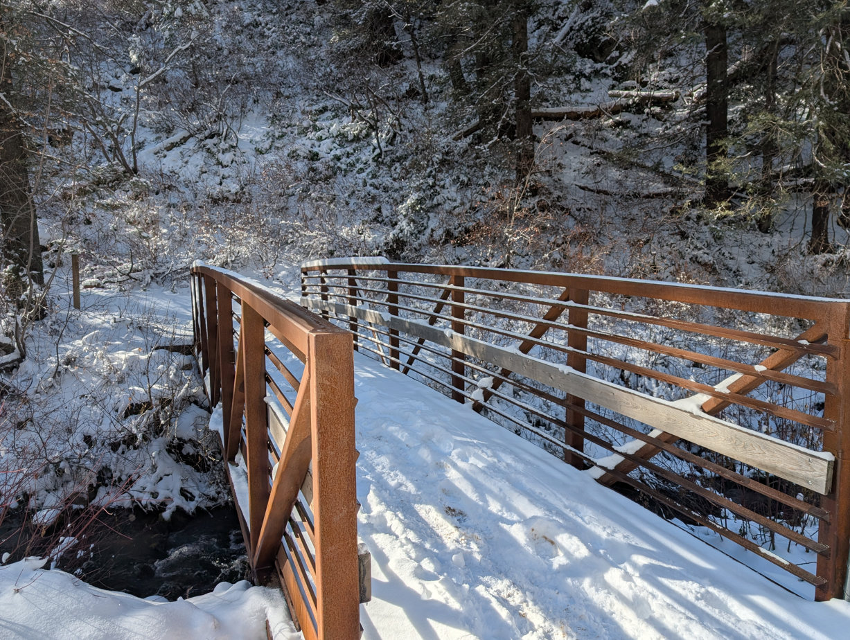 A wooden bridge over a snowy river.