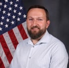 A man standing in front of a flag.