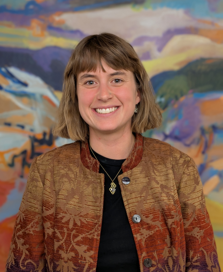 A man smiling in front of a colorful background.