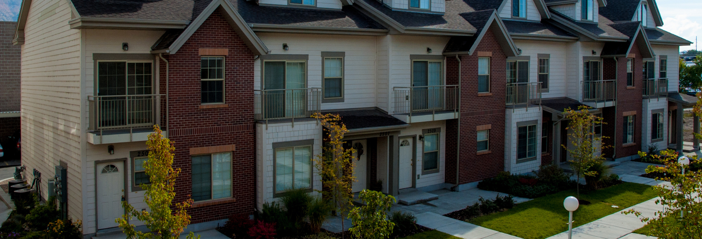 A large brick building with a lawn and trees in front of it.