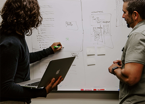 A man and a woman looking at a whiteboard.