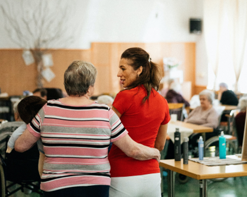 A woman and a man in a room with tables and chairs.