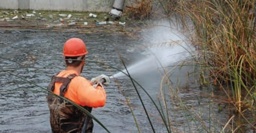 A person in a life jacket holding a fish in a river.