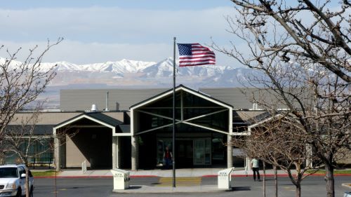 A flag on a pole in front of a building with mountains in the background.