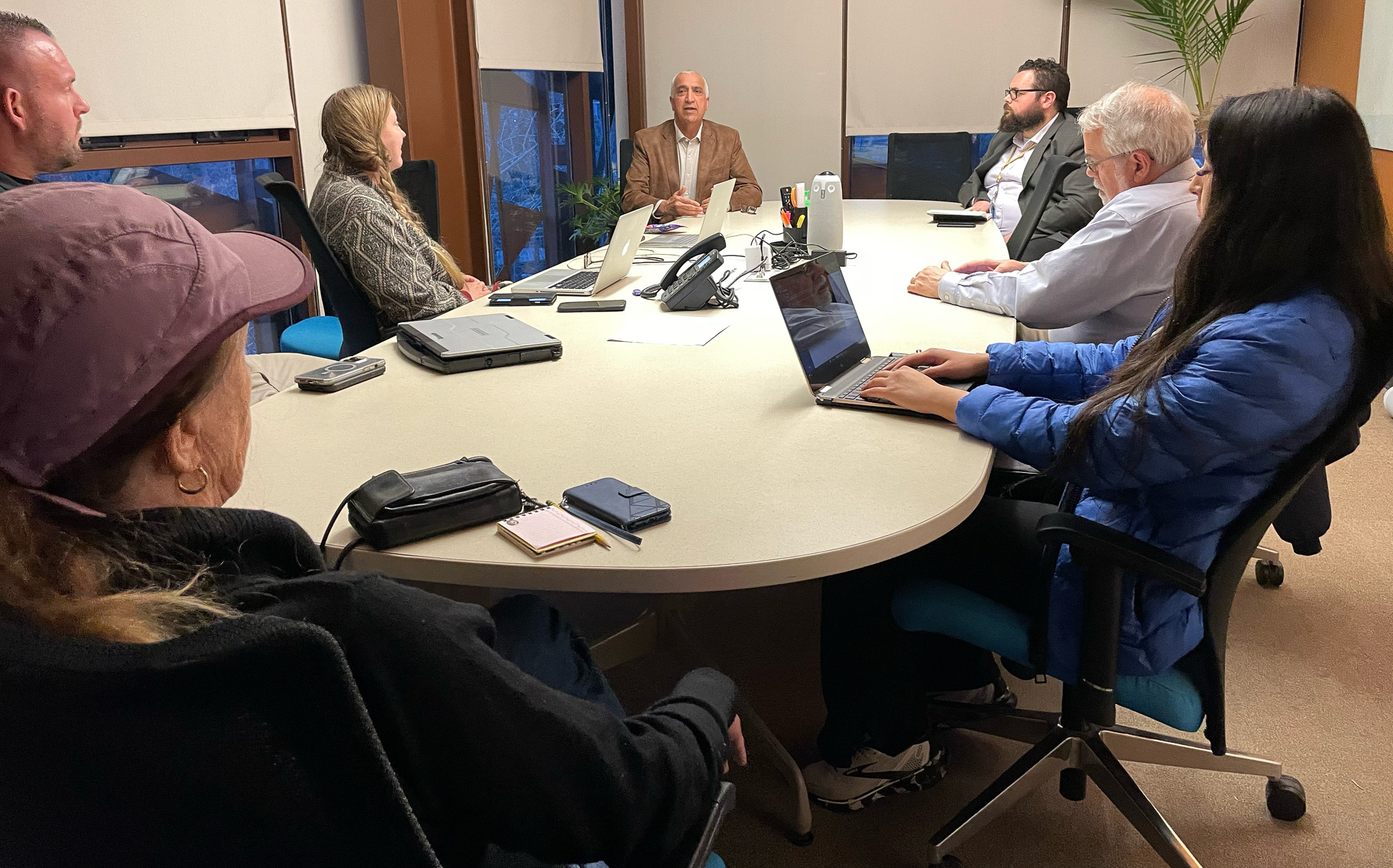 A group of people sitting around a table with laptops.