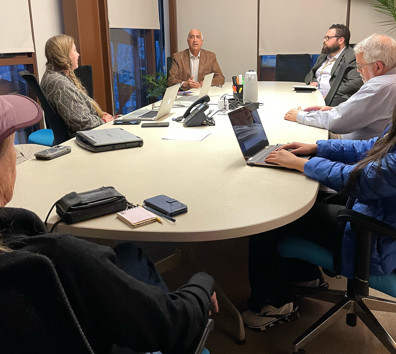 A group of people sitting around a table with laptops.