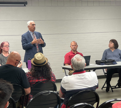 A man speaking to a group of people sitting at tables.