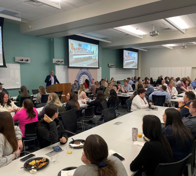 A group of people sitting at tables watching a presentation.