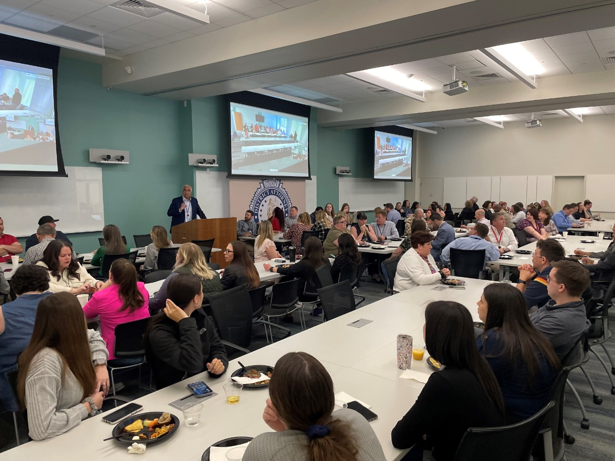 A group of people sitting at tables watching a presentation.