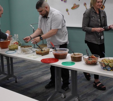 A group of people standing around a table with food on it.