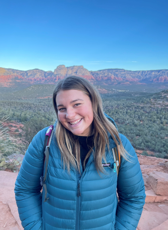 A woman smiling with a canyon in the background.