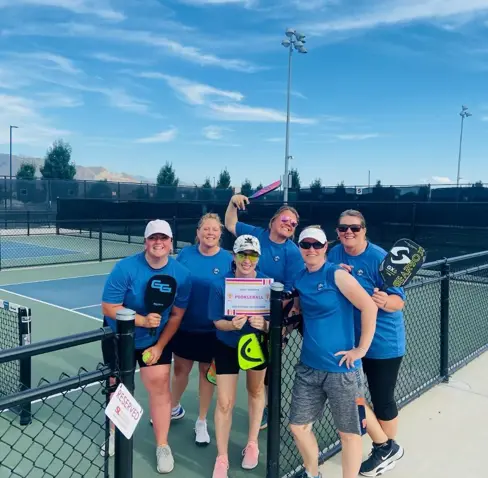 A group of people posing for a photo with a tennis racket.
