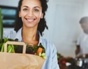 A woman holding a bag of vegetables.