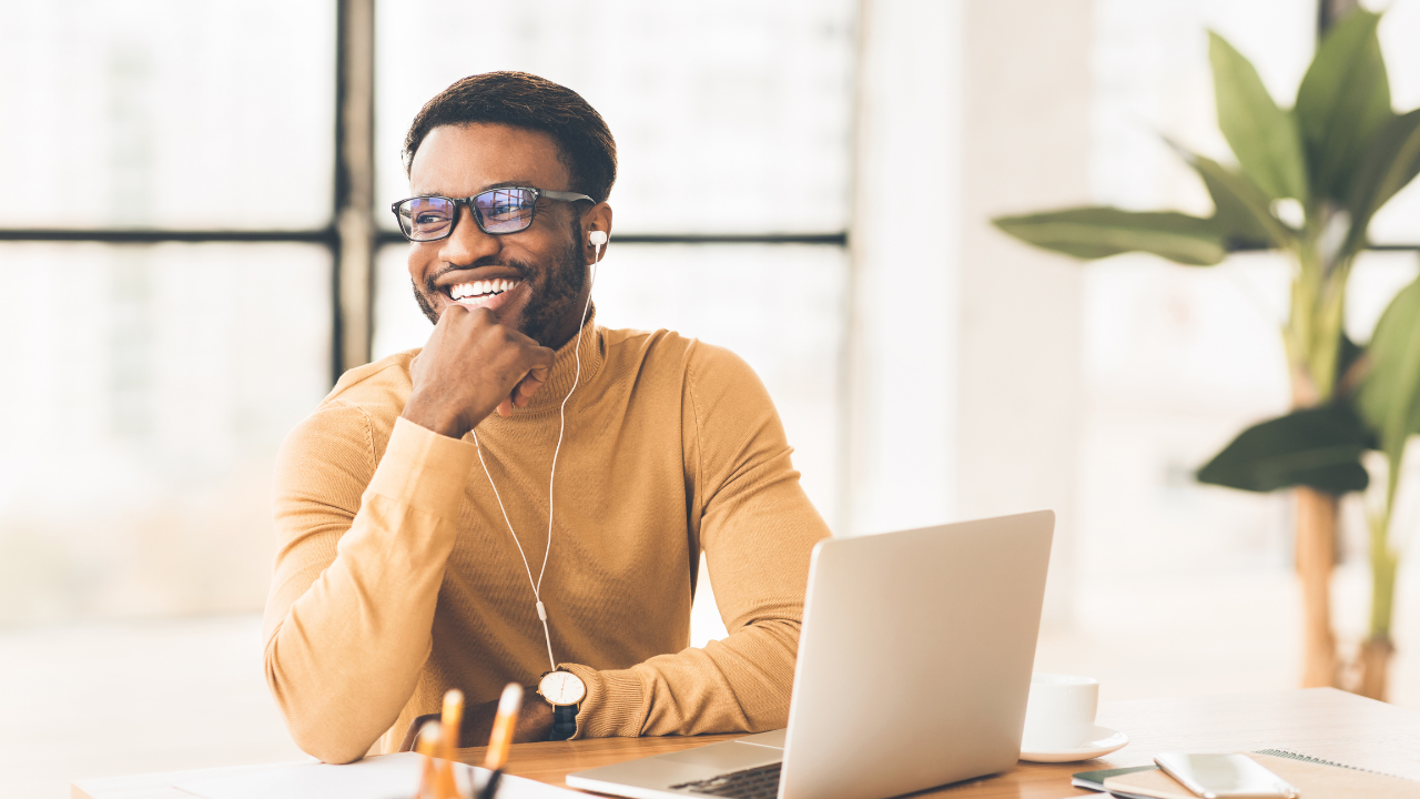A man sitting at a desk with a laptop and headphones.