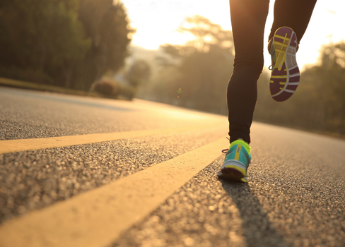 A person's legs and feet on a road.