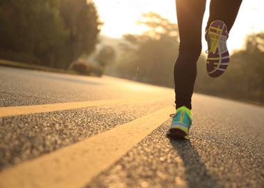 A person's legs and feet on a road.