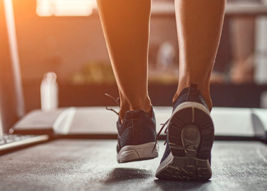 A pair of legs with a pair of shoes on a desk.
