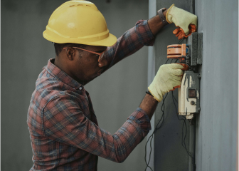A man wearing a hard hat and holding a machine.
