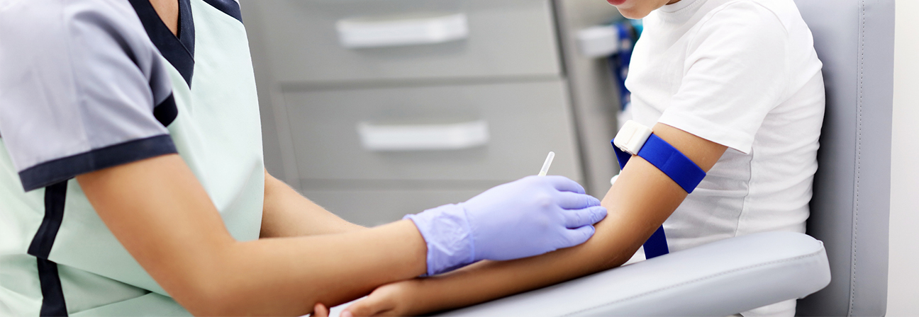 A person in a white lab coat and gloves holding a syringe.