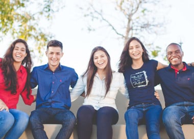 A group of young people sitting together smiling.