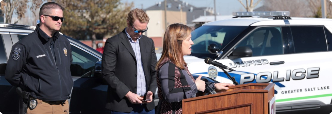 A group of people standing around a police car.