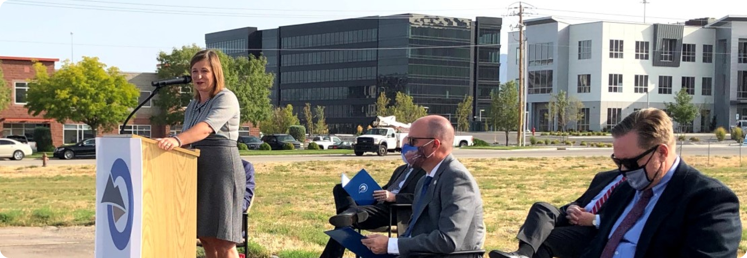 A woman standing next to a man sitting at a table with a laptop.