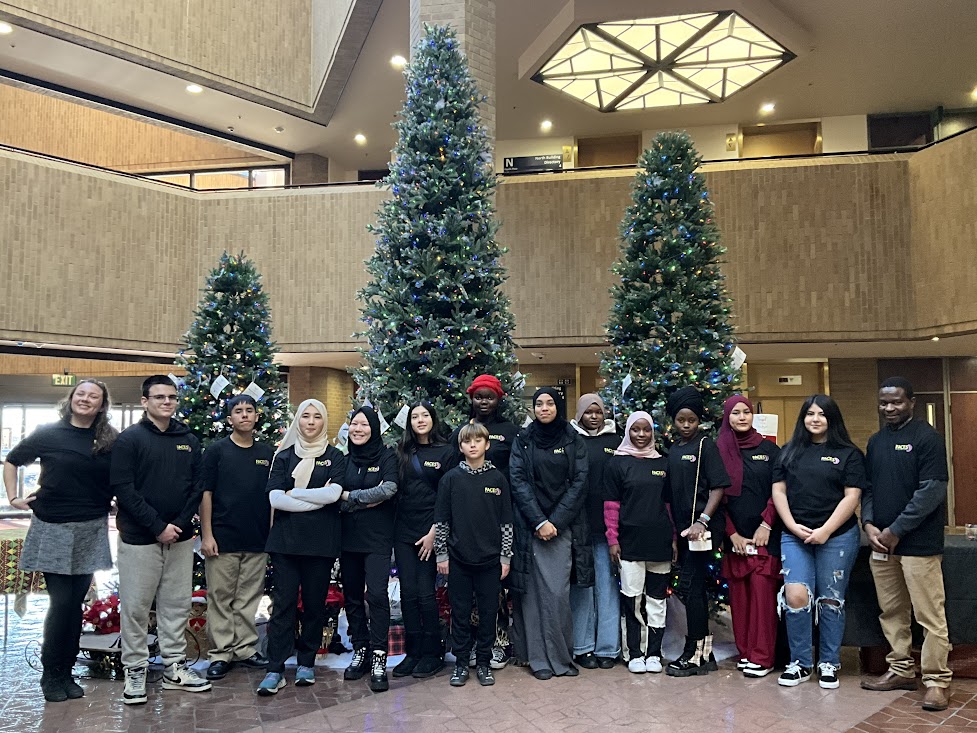 A group of people posing for a photo in front of christmas trees.