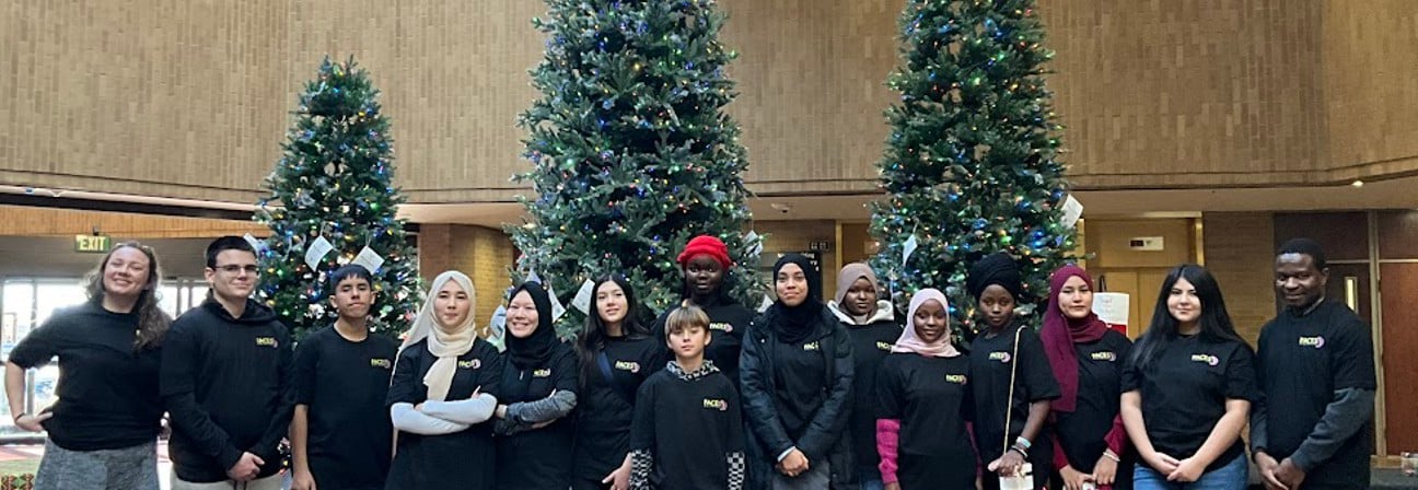 A group of people posing for a photo in front of christmas trees.