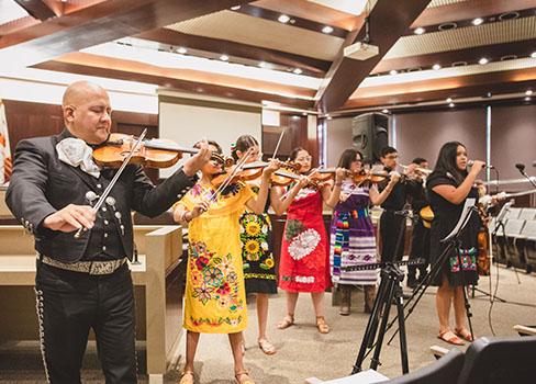 A person playing a violin in front of a group of people.