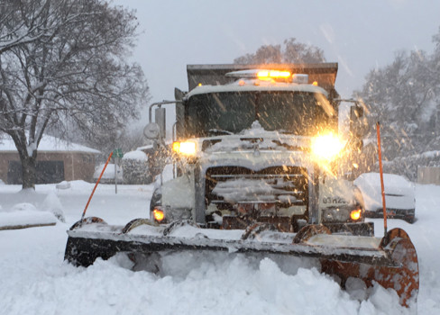 A snow blower in a snowy yard.