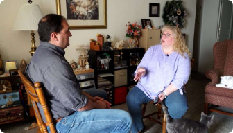 A man and a woman playing a guitar in a living room.
