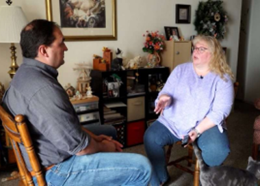 A man and a woman playing a guitar in a living room.