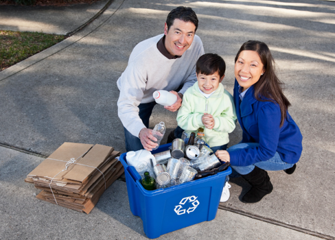 A man and woman with a couple children sitting in a blue shopping cart.