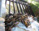 A pile of wood next to a water fall.
