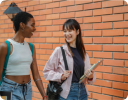 A few women standing in front of a brick wall.