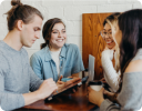 A group of people sitting at a table looking at a computer.