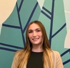A person smiling in front of a wall with a blue and yellow background.