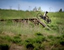 A person riding a bike on a wooden bridge in a field.