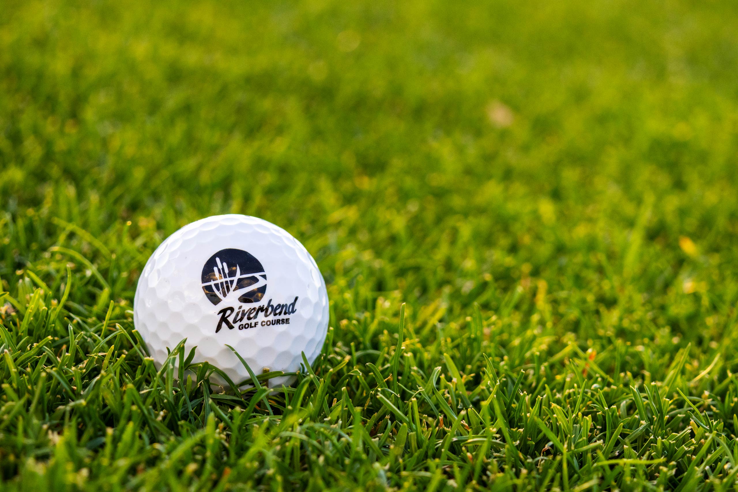 Riverbend Golf Course branded golf ball in green grass.