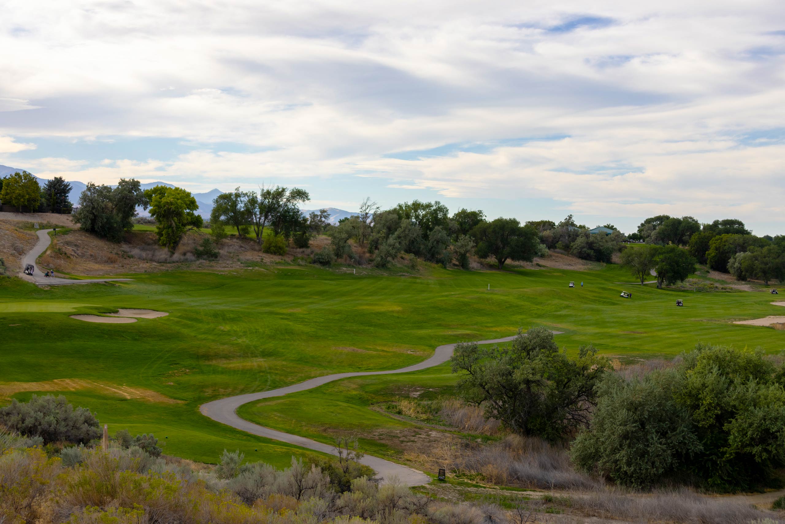 A sweeping view of a fairway, golf cart path, and trees at Riverbend Golf Course in Riverton, Utah.