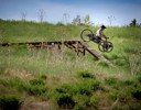 A person riding a bike on a wooden bridge in a field.